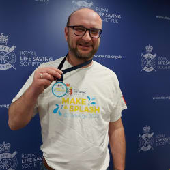 Smiling man wearing a Make a Splash t-shirt and medal