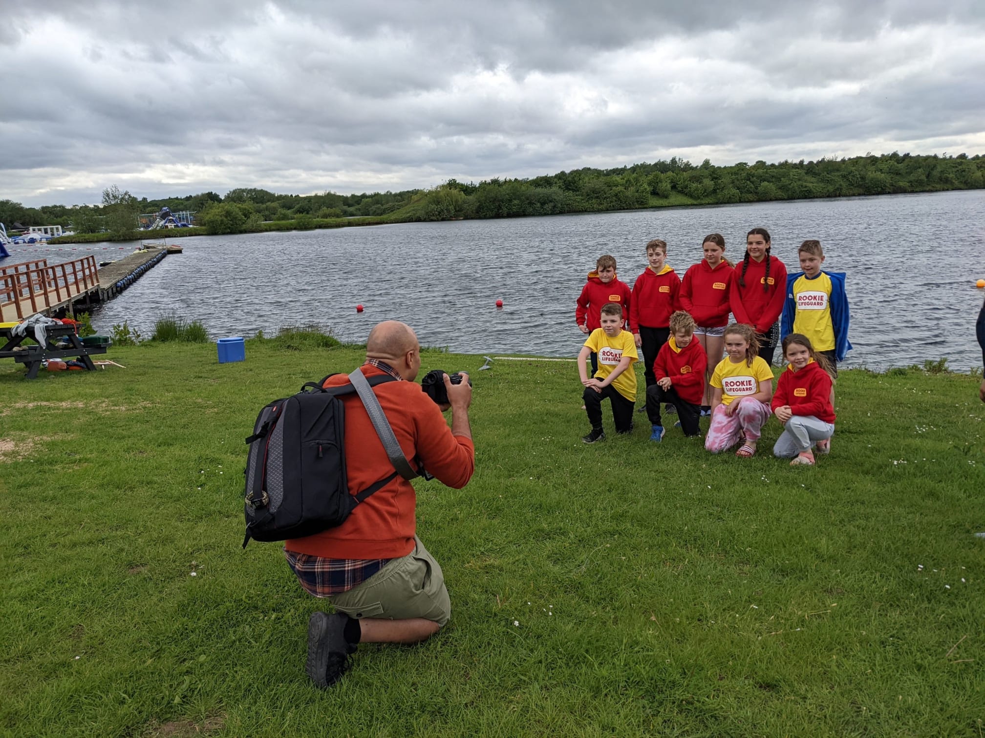 photographer taking a photo of children in Rookie Lifeguard uniforms next to a lake